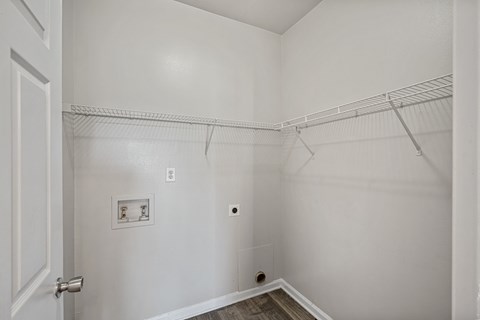 A white closet with a door and a shelf.
