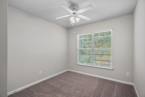 A room with a ceiling fan and a window with blinds.