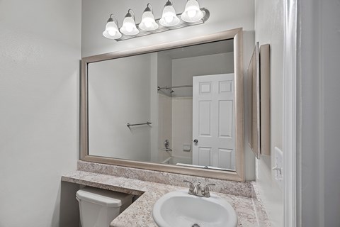 A bathroom with a sink, mirror, and toilet.
