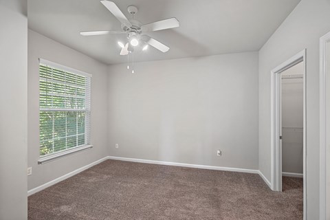 A room with a ceiling fan and carpeted floor.