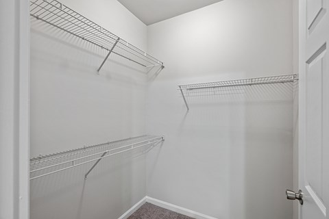 A white closet with two shelves and a door.