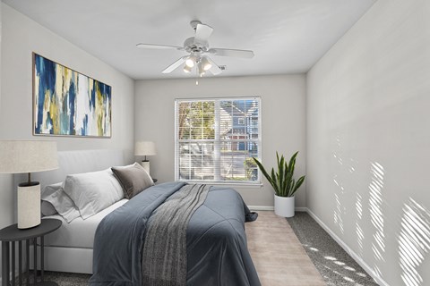 A bedroom with a bed, a ceiling fan, and a painting on the wall.