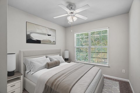 A bedroom with a bed, nightstand, and a painting on the wall.