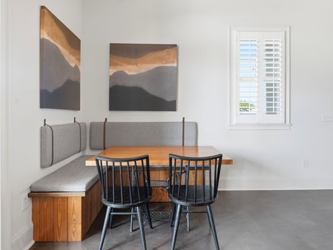 A dining room with a bench, table and chairs.