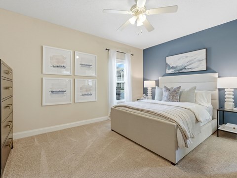 A bedroom with a large bed and a ceiling fan.