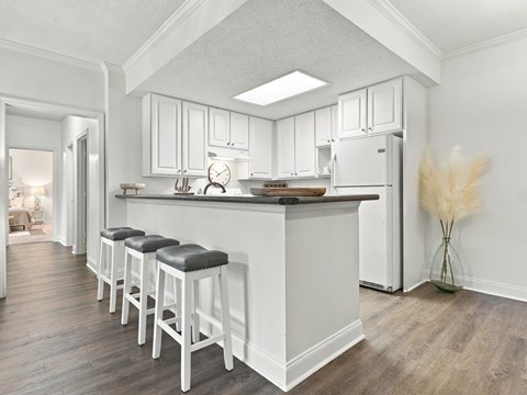A kitchen with white cabinets and a white fridge.