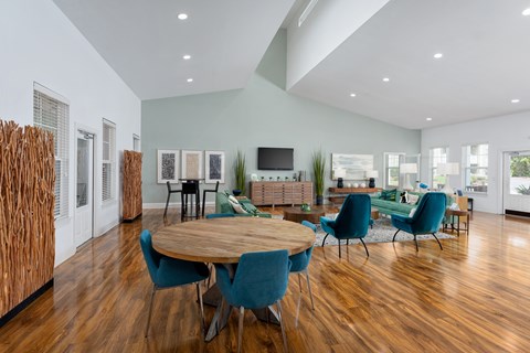 A modern living room with a wooden table and blue chairs.