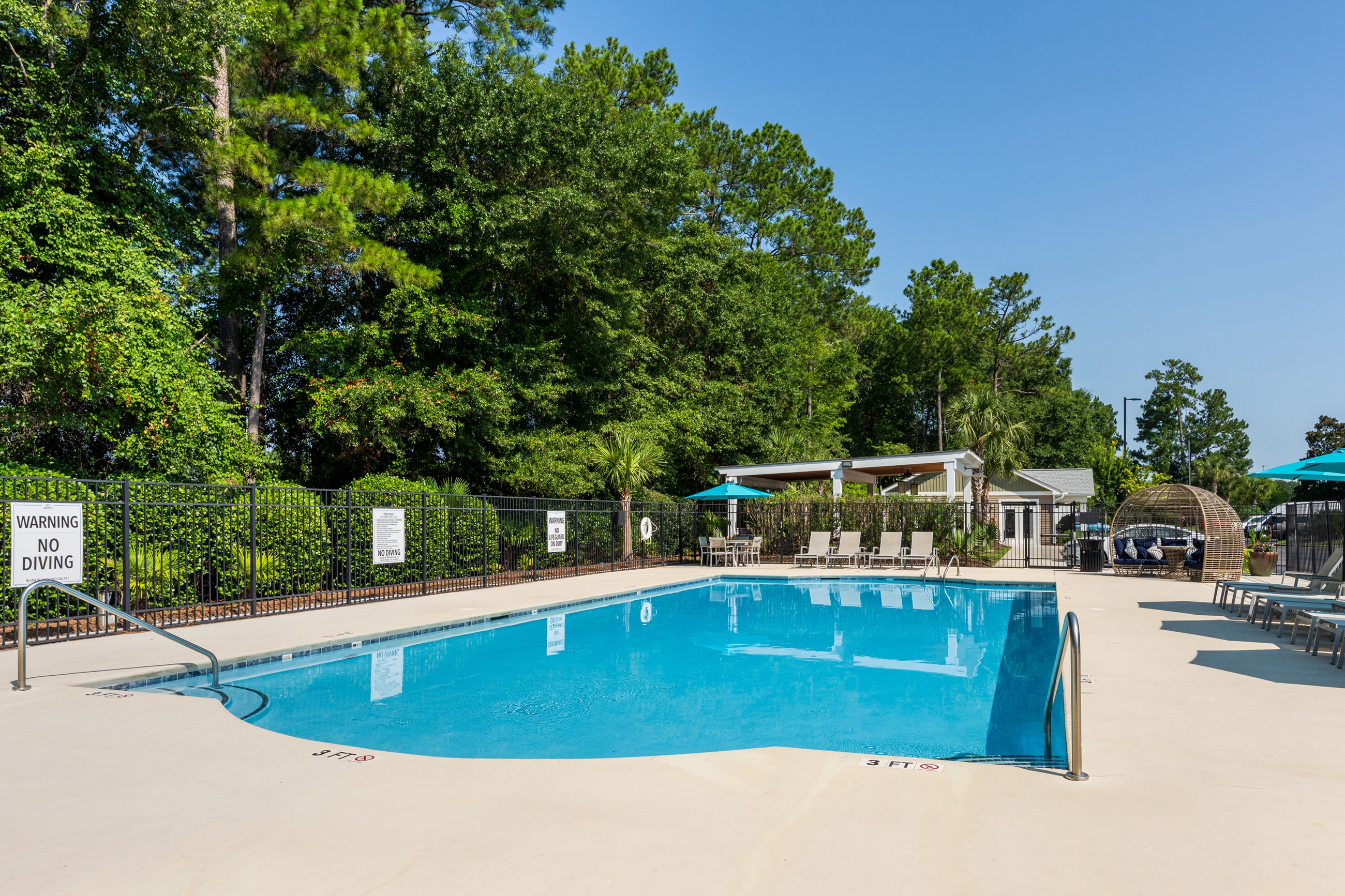 A pool surrounded by trees and a warning sign.