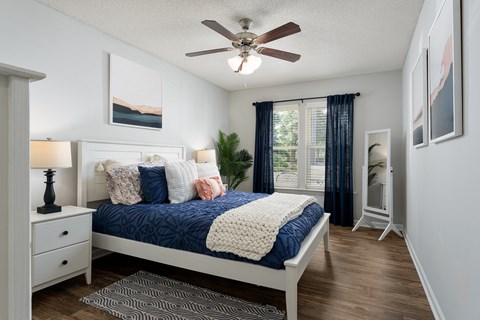 A bedroom with a bed, nightstand, and a ceiling fan.