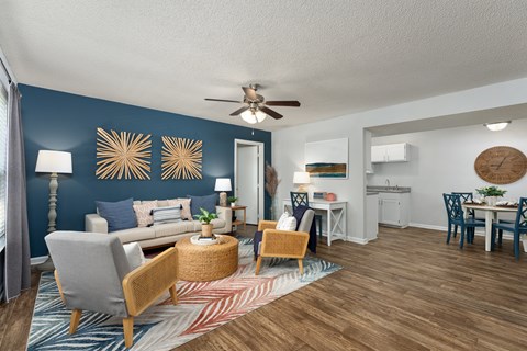 A living room with a grey sofa, a wooden chair, a wicker table, and a ceiling fan.