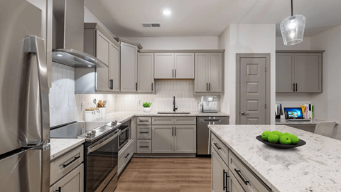 A modern kitchen with a stainless steel refrigerator and wooden floors.