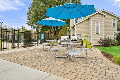A patio with a table and chairs under a blue umbrella.