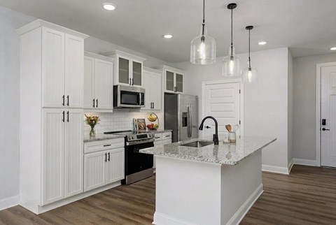 A kitchen with white cabinets and a white island.