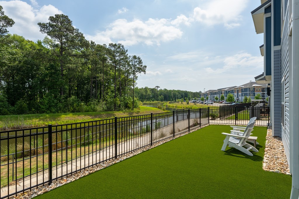 A black metal fence separates a grassy area from a building.