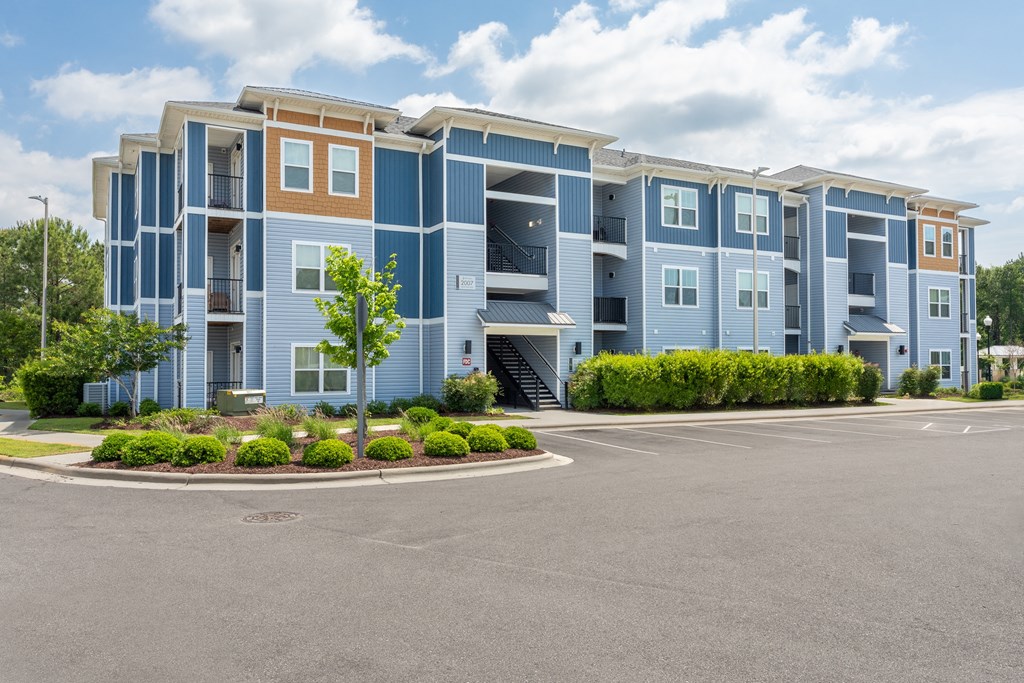 A large apartment complex with a parking lot in front.