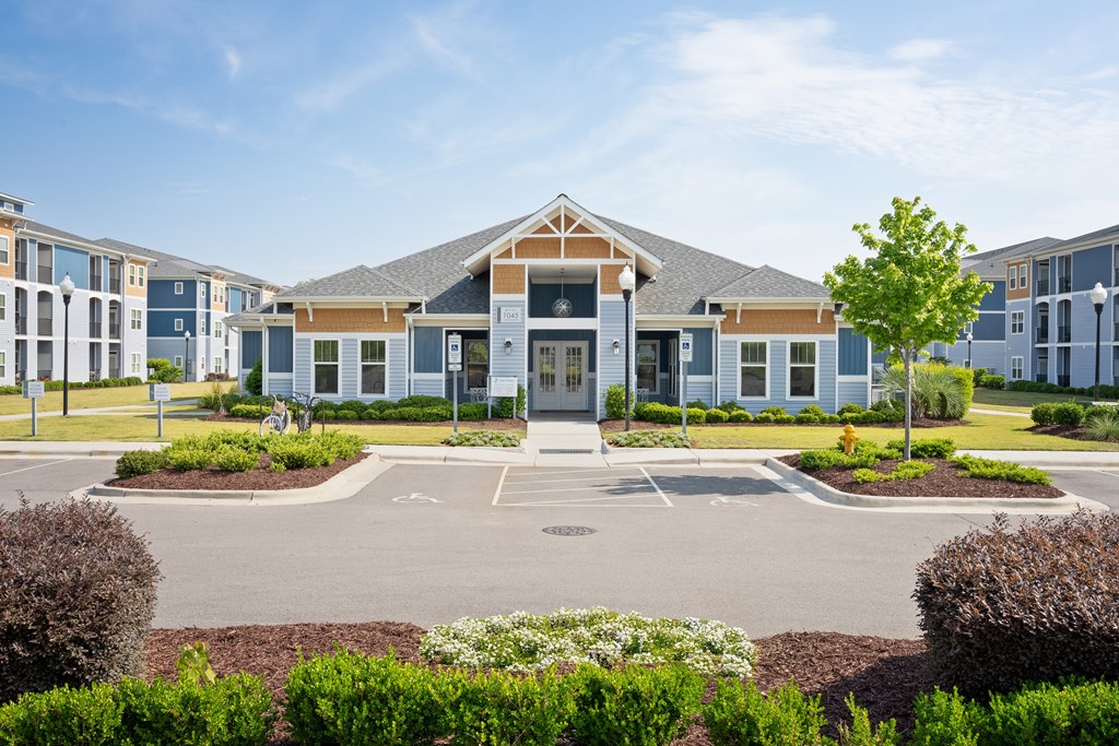A building with a front yard and a parking lot in front.