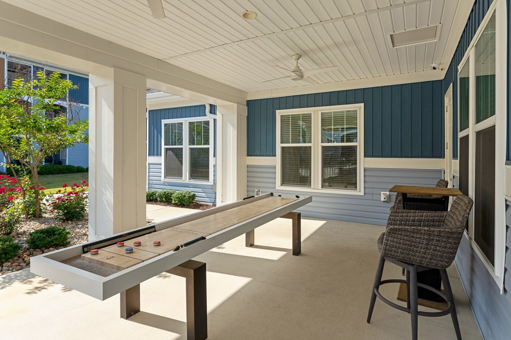 A shaded table with a chair and a pool table with balls on it.
