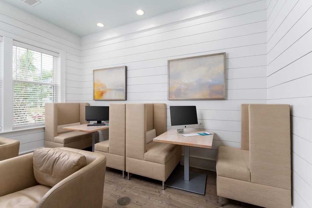 A room with beige chairs and a table with a laptop on it.