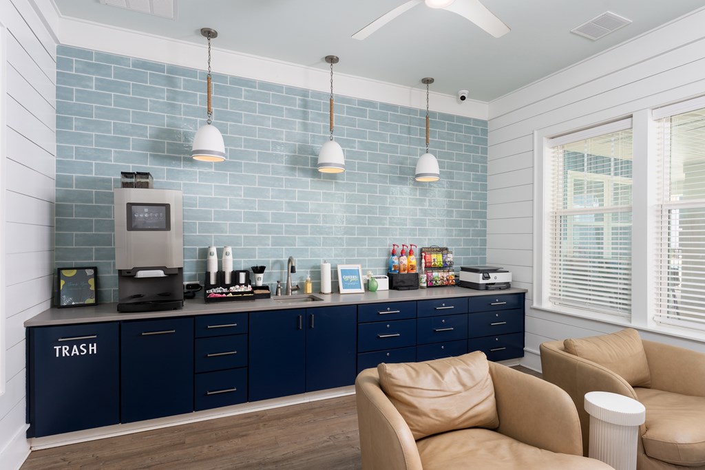 A kitchen with a blue tiled backsplash and dark blue cabinets.