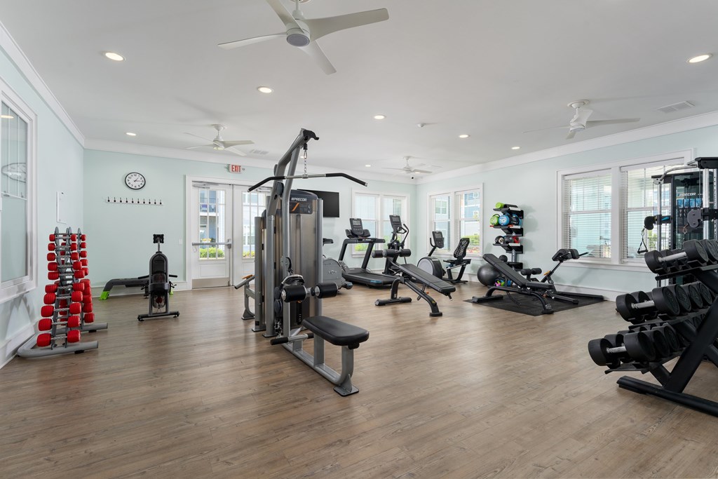 A gym with a variety of equipment including treadmills, weights, and exercise machines.