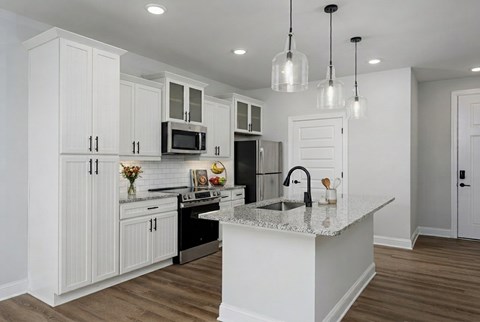 A kitchen with white cabinets and a marble countertop.