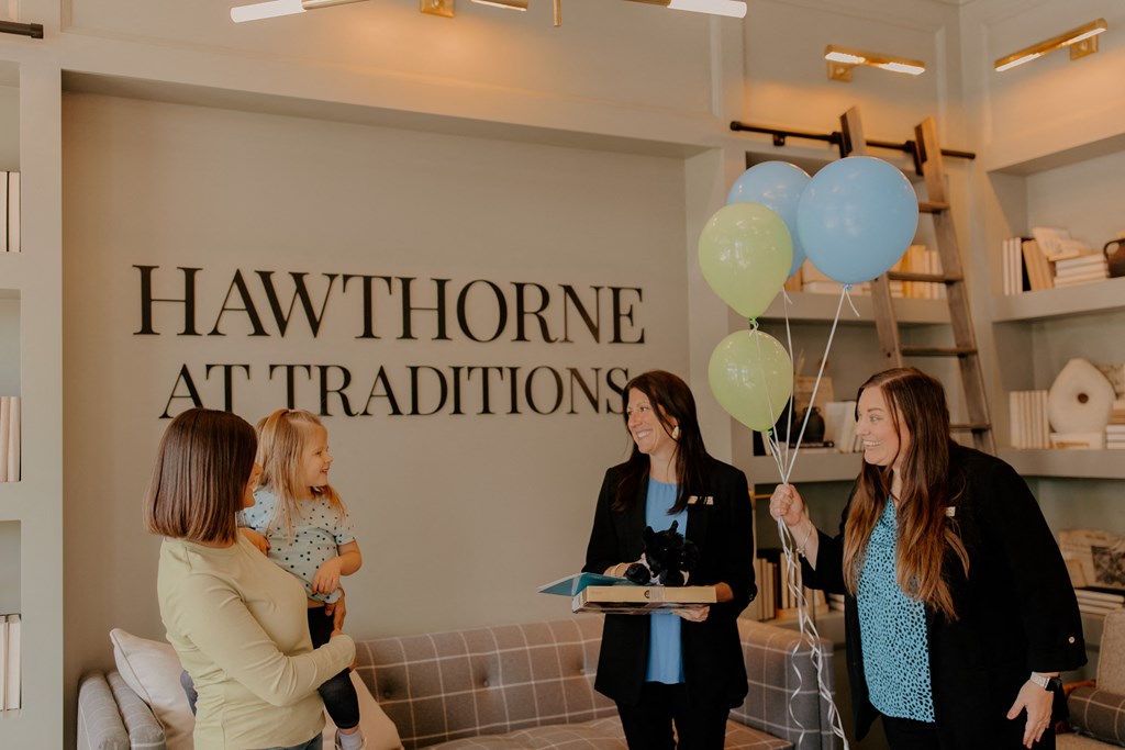 A woman holding a child stands in front of a wall with the words
