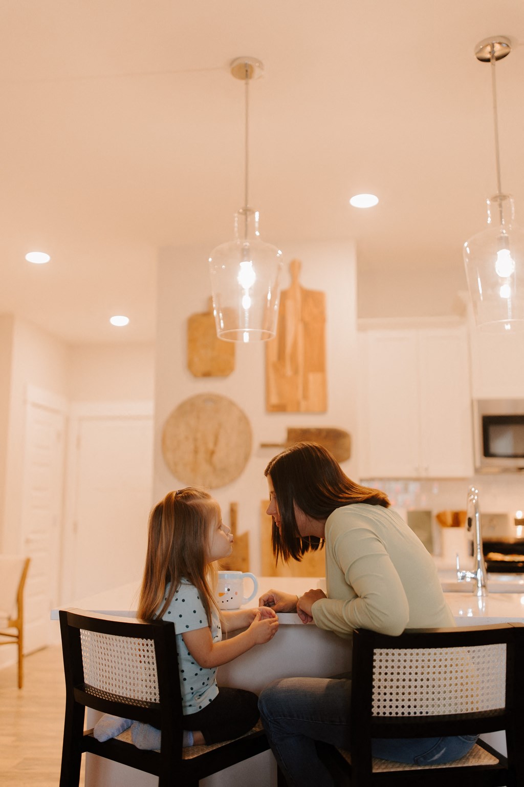 A woman and a girl are sitting at a table in a kitchen.