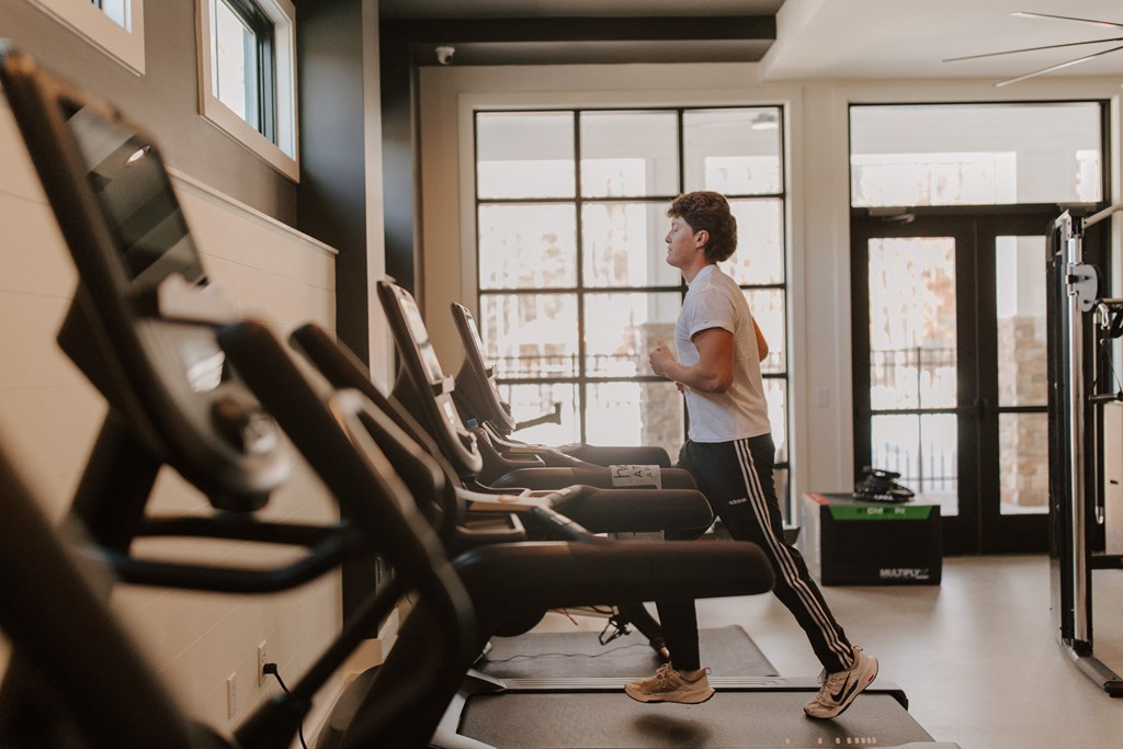 A man is running on a treadmill in a gym.
