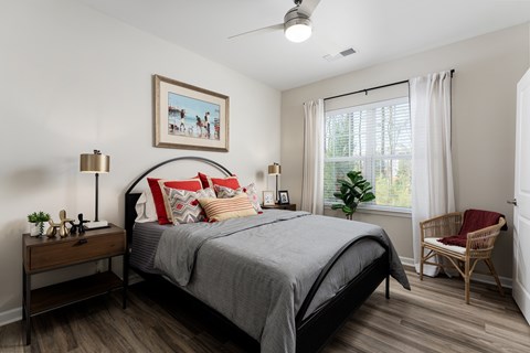 A bedroom with a bed, chair, and a painting on the wall.