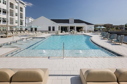 A large swimming pool surrounded by lounge chairs and umbrellas.