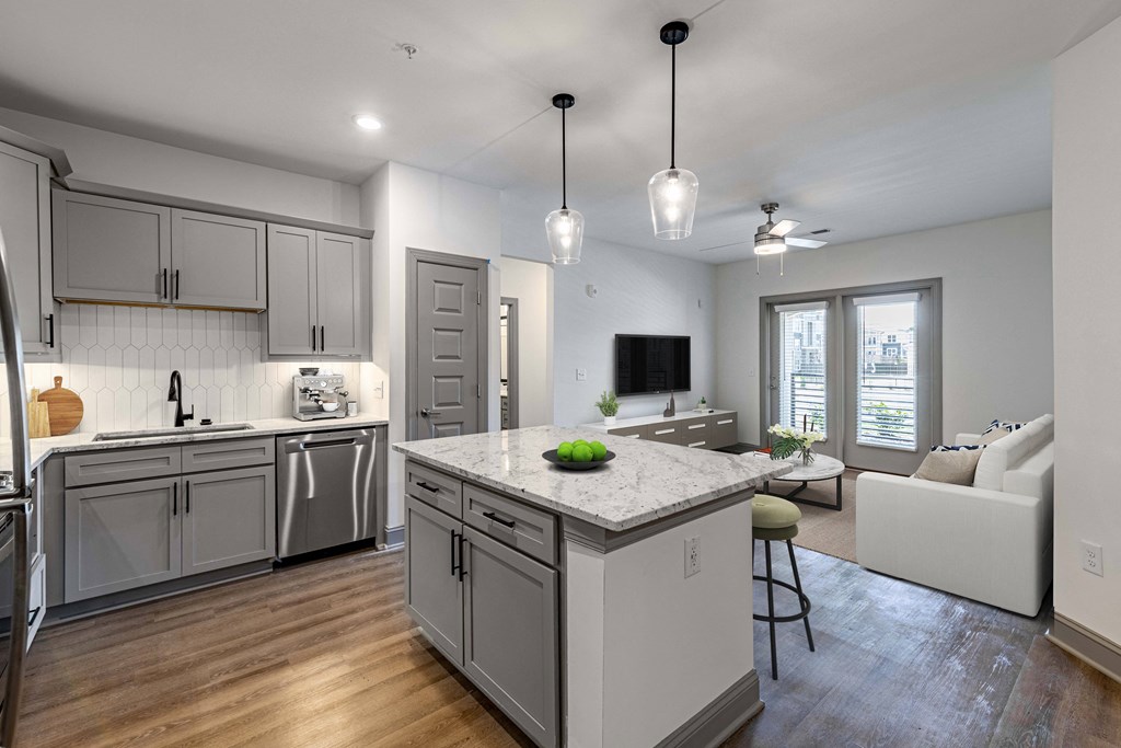 a kitchen and living room with white cabinets and a marble counter top