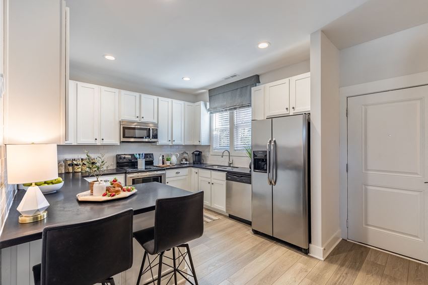 Townhouses in Wilmington NC - Myrtle Landing - Kitchen with White Cabinets, a Breakfast Bar, Wood-Style Flooring, and Stainless-Steel Appliances - Photo Gallery 1