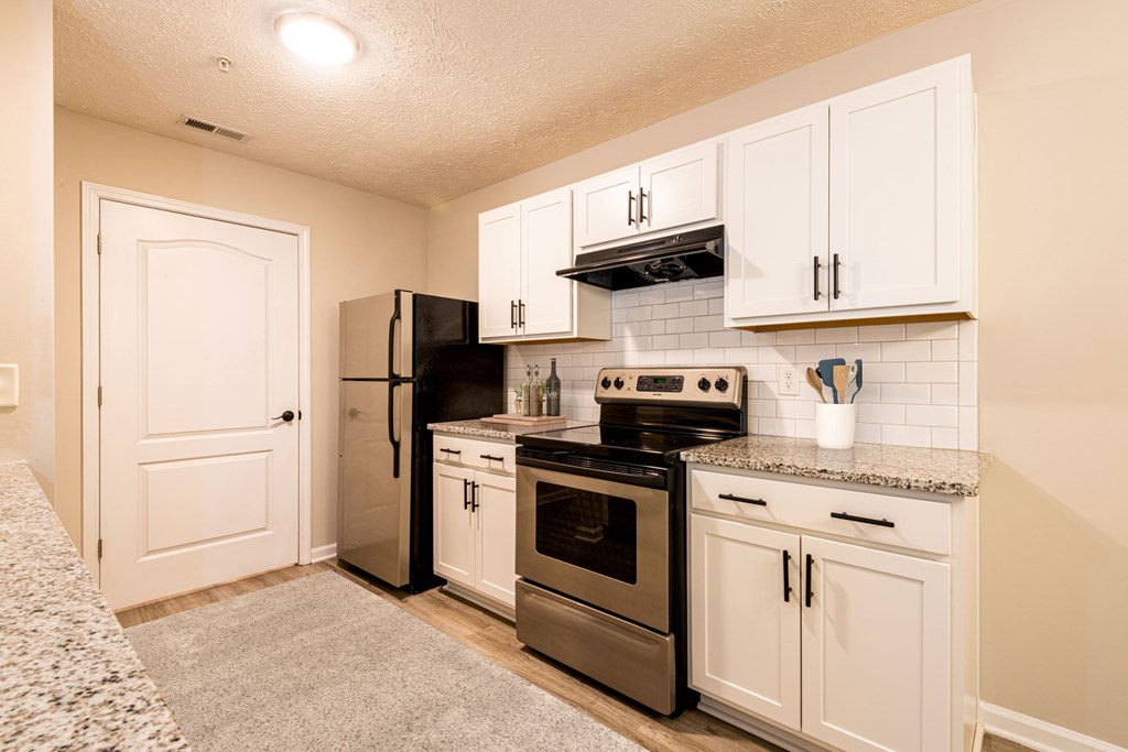 A kitchen with white cabinets and a black refrigerator.