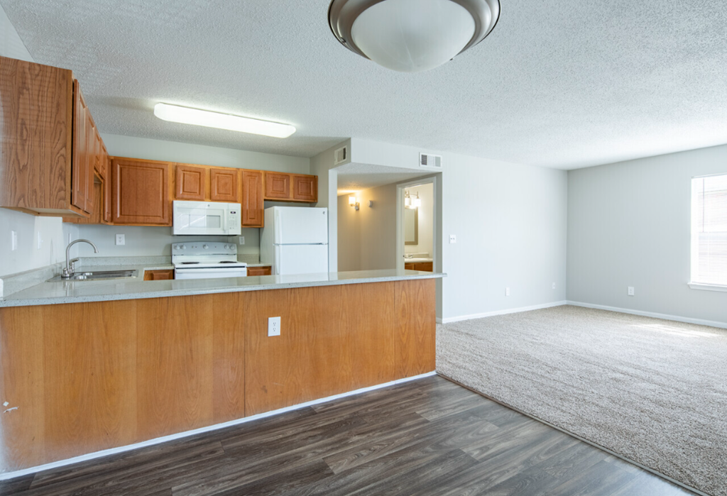 an empty kitchen and living room with wood flooring and white walls