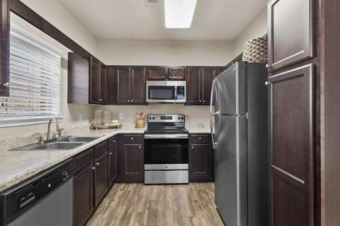A kitchen with dark wood cabinets and stainless steel appliances.