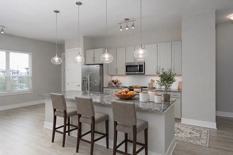 A kitchen with a counter and two chairs.