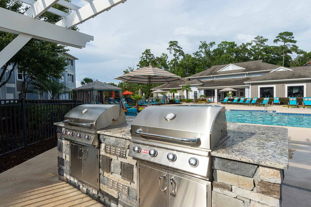 two stainless steel barbecue grills next to a swimming pool