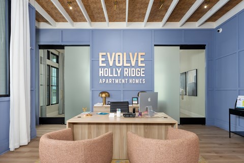 A reception area with a desk and two chairs with a sign  at Evolve Holly Ridge Apartments in Holly Ridge, NC