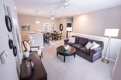 A living room with a couch, a dining table, and a ceiling fan.