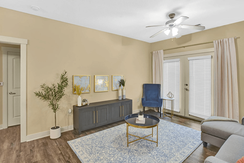 A living room with a blue rug and a ceiling fan.
