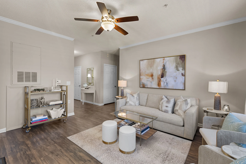 A living room with a white ceiling fan and a painting on the wall.