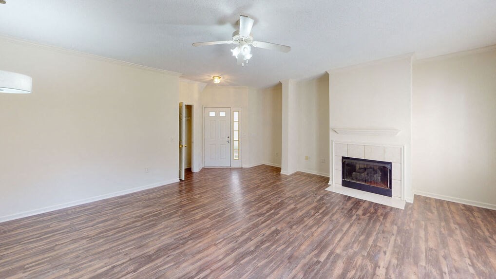 an empty living room with a fireplace and a ceiling fan