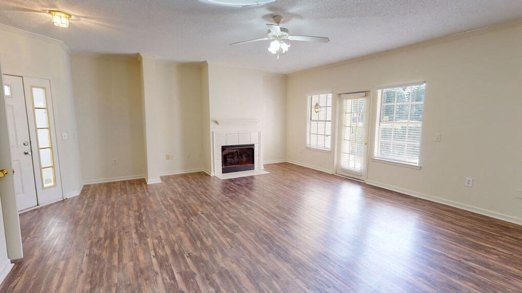 an empty living room with a fireplace and a ceiling fan