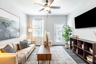 a living room with a ceiling fan and a tv on the wall