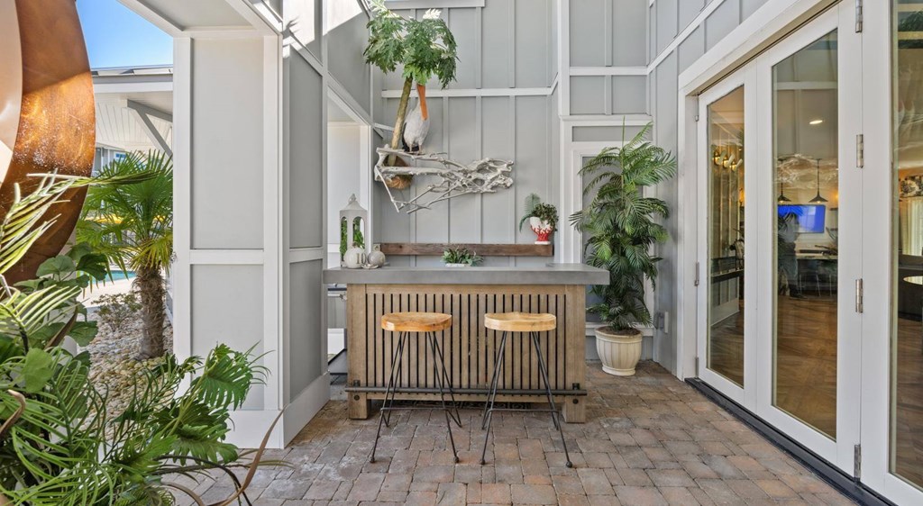 A modern outdoor kitchen area with a wooden counter and a bar stool.