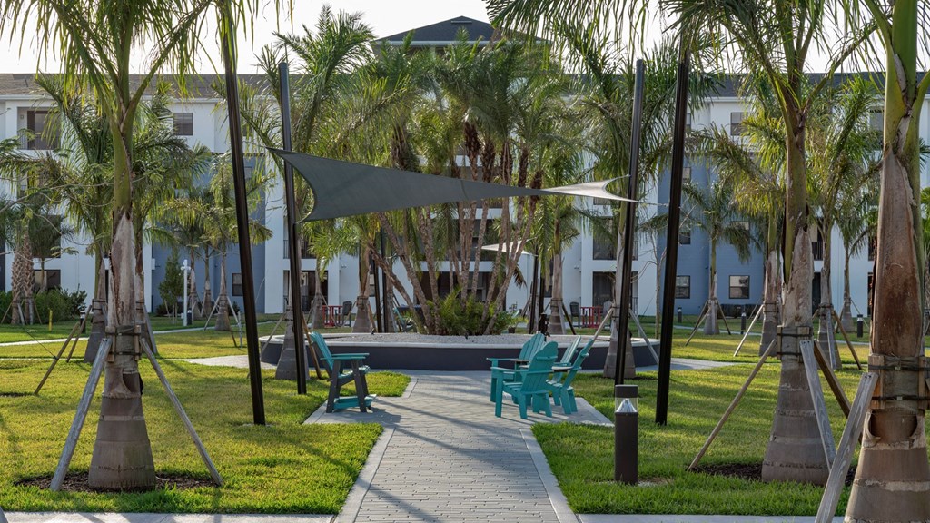 a park with benches and palm trees in front of a building
