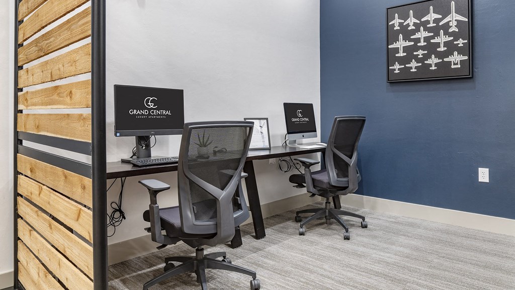 a workspace with two desks with computers and chairs in a room with a blue wall