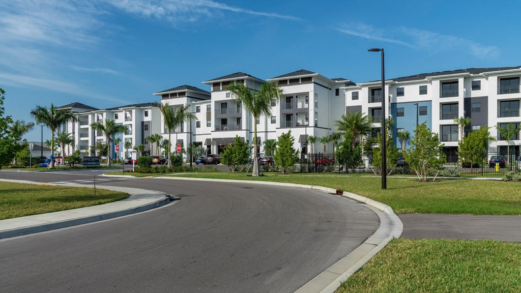 a row of apartment buildings with palm trees near a road