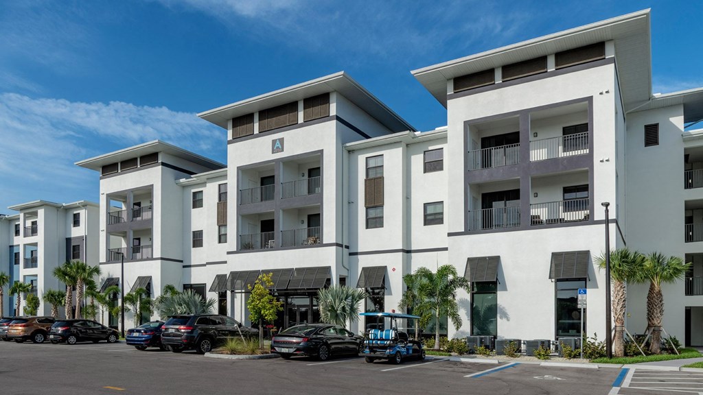 a row of white apartment buildings with cars parked in front of them