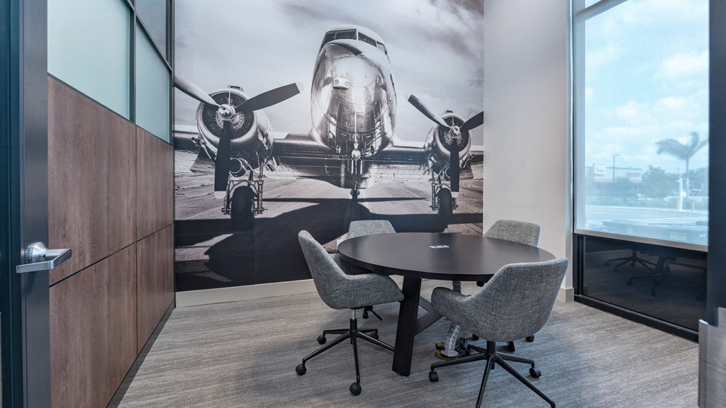 a room with a table and chairs and a mural of an airplane on the wall